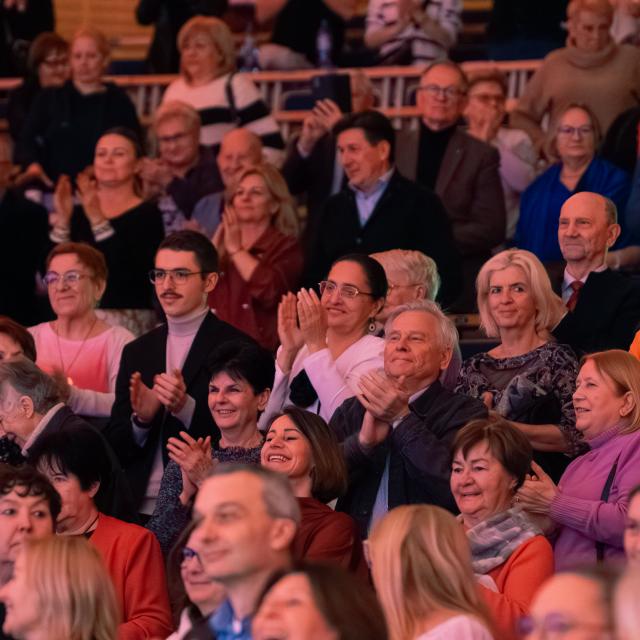 Entuzjastyczna publiczność bije brawo podczas koncertu w auli.